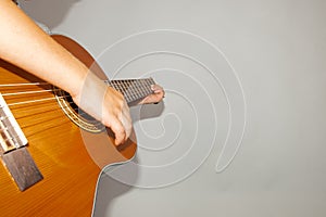 Guitar and strings, man`s hand on a gray background in the studio, wide angle photo