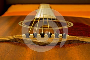 Guitar strings and saddle close up - brown top / soundboard