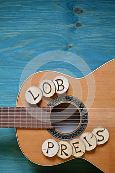 Guitar on teal wood with the word: LOBPREIS