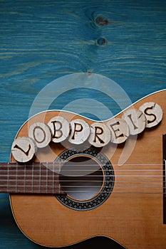 Guitar on teal wood with the word: LOBPREIS