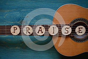 Guitar on teal wood with the word: PRAISE photo