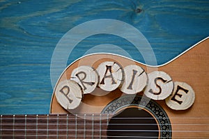 Guitar on teal wood with the word: PRAISE photo