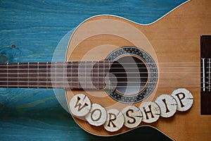 Guitar on teal wood with the word: WORSHIP