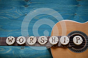 Guitar on teal wood with the word: WORSHIP
