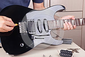 Guitar technician adjusts scale on modern electric guitar