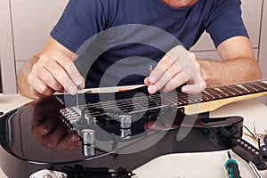 Guitar technician adjusts tremolo bridge on modern electric guitar