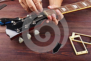 Guitar technician adjusts the trussrod on electric guitar at workplace