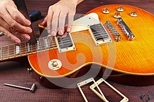 Guitar technician checking the action of strings on electric guitar at workplace