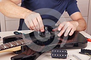 Guitar technician checking radius of strings on modern electric guitar