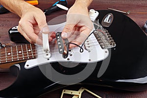 Guitar technician selects pickup for replacement on electric guitar