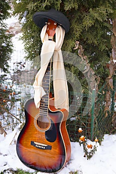 Guitar to a peak-cap with a scarf on snow