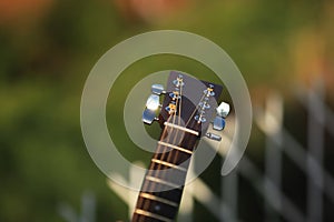 Guitar tuner. Wooden guitar on a natural blurred background. Guitar tuning. The guy tunes the guitar