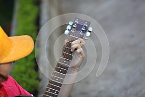 Guitar tuner. Wooden guitar on a natural blurred background. Guitar tuning. The guy tunes the guitar