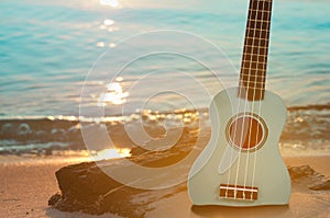 Guitar ukulele on sand beach with clear water and blue sky. Travel and lifestyle Concept.