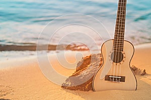 Guitar ukulele on sand beach with clear water and blue sky. Travel and lifestyle Concept.