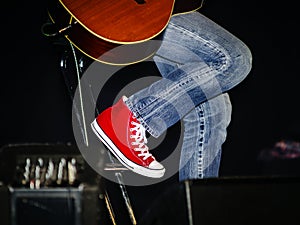Guitarist dressing in jeans and red gumshoes