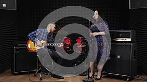 Guitarist and female singer are performing live concert. Girl vocalist is singing lyric love song in recording vocal studio. Music