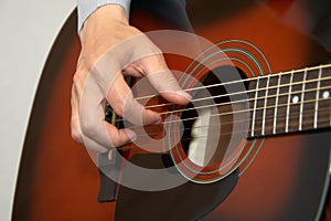 Guitarist hand, fingers playing acoustic guitar photo