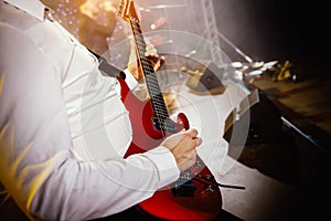 Guitarist hand play guitar on concert stage with red guitar
