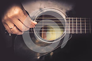 Guitarist Hand playing on acoustic guitar fretboard vintage style