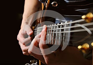 Guitarist hands playing guitar over black