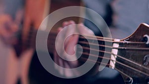 Guitarist hits the strings of the guitar, close up mens fingers playing music on guitar in slow motion.