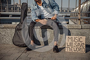 Guitarist holding hot drink on the street