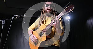 Guitarist man plays an acoustic guitar Close-up at studio
