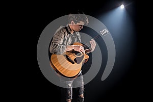 Guitarist, music. A young man plays an acoustic guitar on a black isolated background