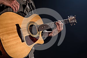 Guitarist, music. A young man plays an acoustic guitar on a black isolated background