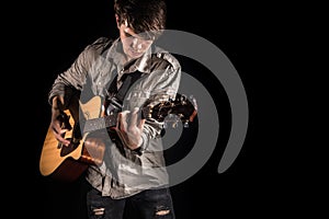 Guitarist, music. A young man plays an acoustic guitar on a black isolated background