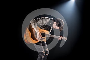 Guitarist, music. A young man plays an acoustic guitar on a black isolated background