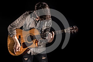 Guitarist, music. A young man plays an acoustic guitar on a black isolated background