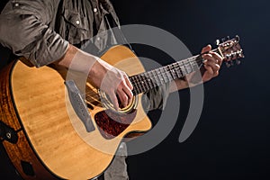 Guitarist, music. A young man plays an acoustic guitar on a black isolated background