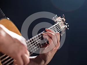 Guitarist, music. A young man plays an acoustic guitar on a black isolated background