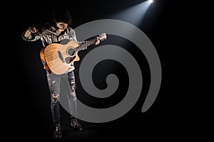 Guitarist, music. A young man plays an acoustic guitar on a black isolated background