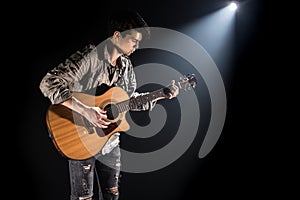 Guitarist, music. A young man plays an acoustic guitar on a black isolated background