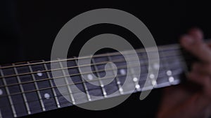 Guitarist playing acoustic guitar in dark room close up.