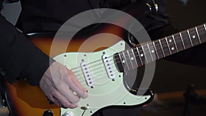 Guitarist playing electric guitar music on stage at rock concert indoors.