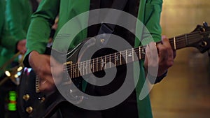 Guitarist playing electric guitar music on stage at rock concert indoors.