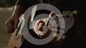 The guitarist plays a classic wooden guitar. A musician plays an acoustic guitar in a dark room