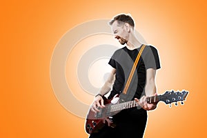 The guitarist plays the electric guitar on orange background