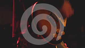 The guitarist plays on guitar in a dark room. Hands of a Guitar player playing the guitar