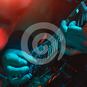 The guitarist plays the guitar in the spotlight. Hands of a Guitar player playing the guitar. Low key