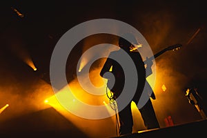 Guitarist plays solo. silhouette of guitar player in action on music stage. popular music rock band performs on stage