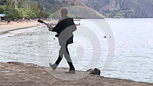 Guitarist plays and walks against beach