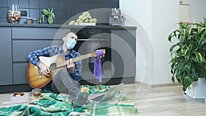 Guitarist in protective medical face mask emotionally singing and playing on guitar lyric romantic song sitting on the floor at ki