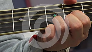 The guitarist's hand presses the chords on the guitar neck, close-up