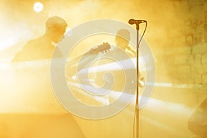 Guitarist silhouette perform on a concert stage. Abstract musical background. Music band with guitar player. Playing