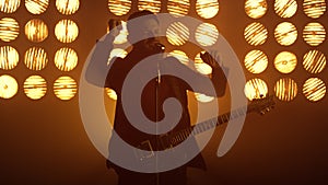 Guitarist singing microphone enjoying process at spotlights. Man performing song